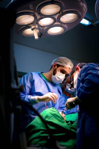 Medical professionals performing surgery in a well-equipped operating room, wearing surgical masks and gowns.